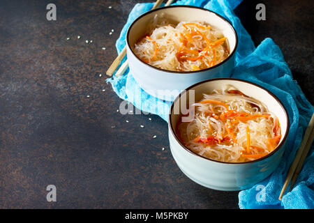 Funchoza Salat mit Reis Nudeln mit Paprika, Tomaten und Paprika auf einem dunklen Stein oder Schiefer Hintergrund, kopieren. Stockfoto