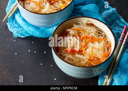 Funchoza Salat mit Reis Nudeln mit Paprika, Tomaten und Paprika auf einem dunklen Stein oder Schiefer Hintergrund, kopieren. Stockfoto