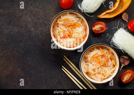 Funchoza Salat mit Reis Nudeln mit Paprika, Tomaten und Paprika auf einem dunklen Stein oder Schiefer Hintergrund, kopieren. Stockfoto