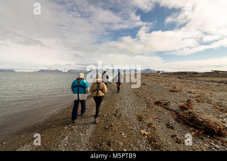 Svalbard, Norwegen, 3. August 2017: Gruppe von Touristen Wandern am Strand bei Prins Karls Forland auf Spitzbergen, auf der Suche nach Deutscher Pfadfinderverband. Stockfoto