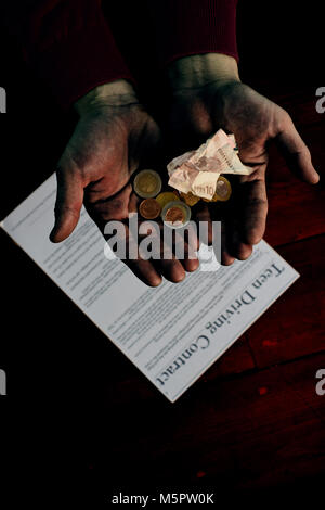 Kleine Münzen verschiedener Wert und zerknüllten Geldschein in offenen Hände vor dem Hintergrund der Vertrag. Stockfoto