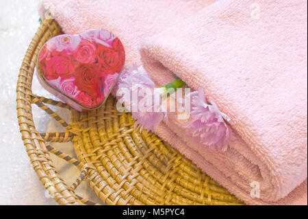 Handtuch, Container mit Seife in Form eines Herzens in den geflochtenen Platte mit zwei Gartennelke-blumen Stockfoto