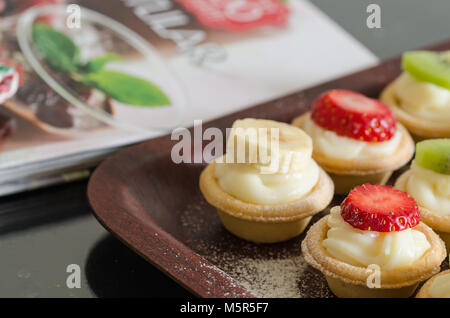 Creme gefüllte Törtchen. Es gibt Erdbeeren, Kiwi, Bananen, die auf der Oberfläche. Stockfoto