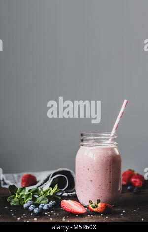 Rosa strawbery Smoothie in Glas mit Strohhalm auf grauem Hintergrund. Kopieren Sie Platz für Text, getönten Bild. Gesunde Lebensweise, gesunde Ernährung Konzept Stockfoto