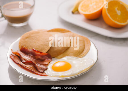 Frühstück mit Pfannkuchen, Eier, Schinken und Obst. Stockfoto