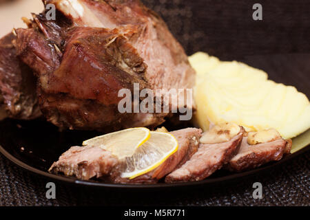Ein Stück saftig gebratenes Fleisch mit Zitrone und Knoblauch schneiden sie in einige Stücke Stockfoto