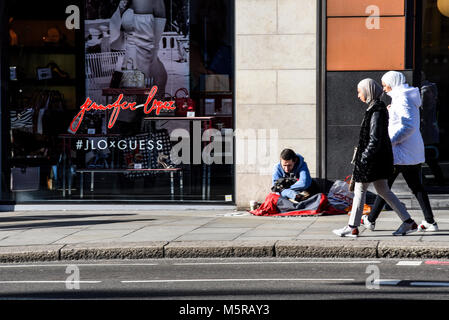 Obdachloser in Brompton Road, Knightsbridge, London auf der Straße mit Passanten Stockfoto