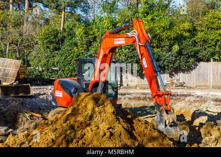 Große orange schwere Anlage mechanische Bagger auf einer Baustelle geparkt nach graben Ausgrabungen für die Grundlagen einer neuen Wohnanlage Stockfoto