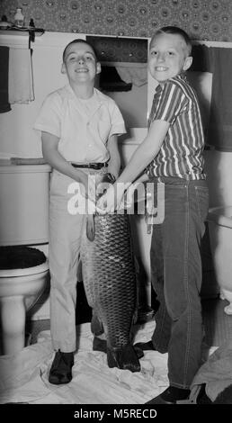 Zwei Jungen, die Gefahr, den Zorn ihrer Mutter durch einen großen Karpfen in der Familie Badezimmer, Ca. 1950. Stockfoto