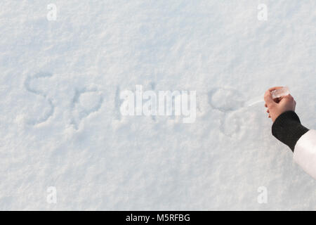 Hand schrieb das Wort Frühling Eiszapfen auf dem Schnee Stockfoto