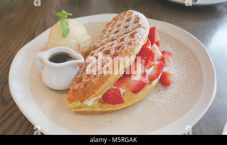 Flauschig und lecker aussehenden Erdbeercreme Waffeln mit Eis und Sirup Stockfoto