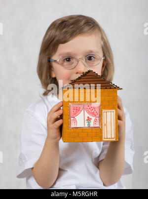 Junge von fünf Jahren hält handgefertigte Karton Papier Haus. Nahaufnahme Stockfoto
