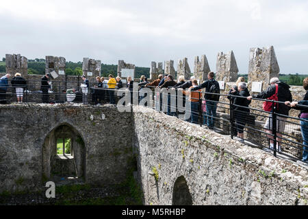 Eine lange Schlange von Besuchern Ansehen einer der Besucher mit Hilfe von einem Mitglied der Burg Personal der Blarney Stone oben zu küssen. Stockfoto