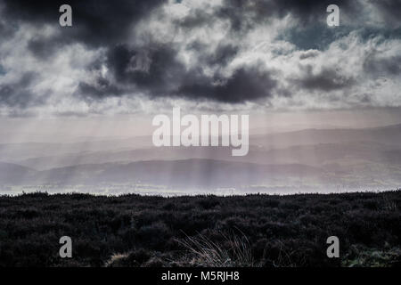 Drei horizontale Schicht moody Landschaft mit beleuchteten dunkle Wolken, Misty Hills mit Sonnenstrahlen und einem dunklen Heather Moor. Stockfoto