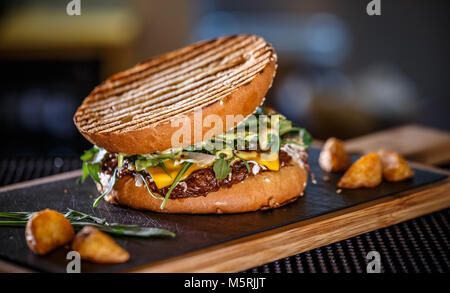 Frische leckere Burger mit Kartoffel Keil auf schwarzem Schiefer board Stockfoto