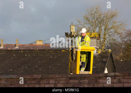 Ein BT-Telefon Ingenieur in einem Korb Kran/Cherry Picker arbeitet auf einem telegrafenmast über Dächer Stockfoto