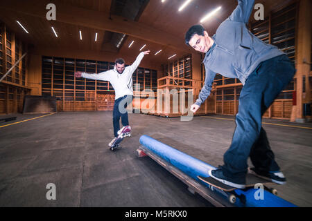 Zwei junge Skater sind sie Tricks mit ihren Skateboards in einen Indoor skate Hall. Stockfoto