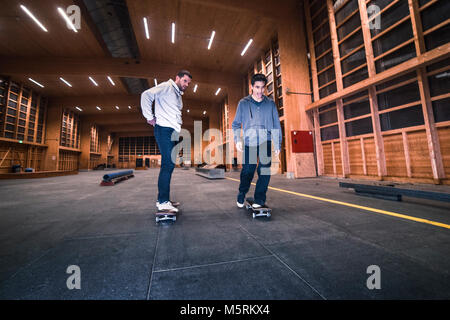 Zwei junge Skater üben mit ihren Skateboards in einen Indoor skate Hall. Stockfoto