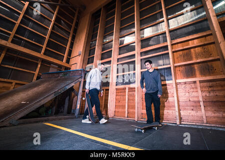 Zwei junge Skater üben mit ihren Skateboards in einen Indoor skate Hall. Stockfoto