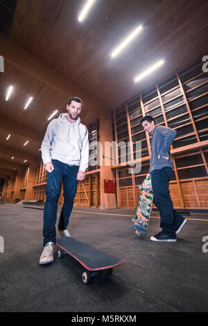 Zwei junge Skater üben mit ihren Skateboards in einen Indoor skate Hall. Stockfoto