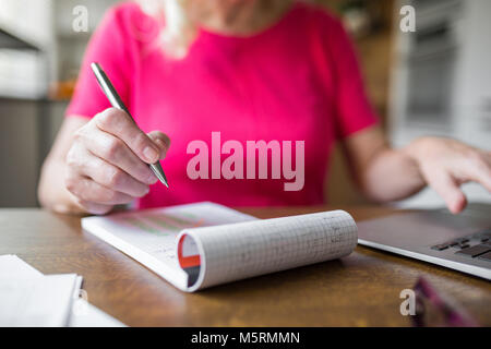 7/8-Portrait von älteren Frau zu Hause Notizen arbeiten Stockfoto