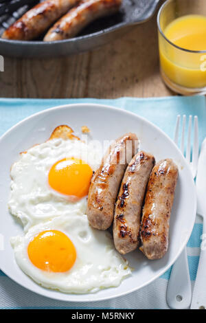 Spiegeleier mit Würstchen und Orangensaft Stockfoto