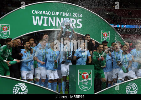 Wembley Stadion, London, UK. 25 Feb, 2018. Vincent Kompany (MC) hebt den Cup wie Champagner ist rund um die siegreiche Mannschaft an der Carabao Cup Finale - Arsenal v Manchester City, im Wembley Stadion, London gesprüht, am 25. Februar 2018. ** Dieses BILD IST FÜR DIE REDAKTIONELLE VERWENDUNG ** Quelle: Paul Marriott/Alamy leben Nachrichten Stockfoto