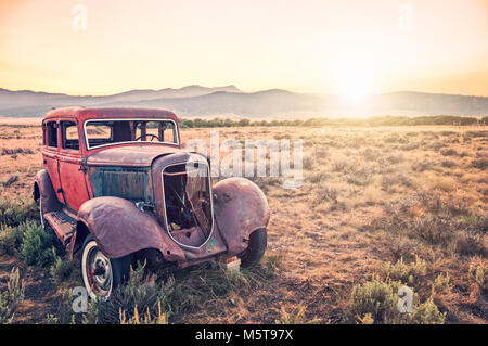 Alten rostigen Antique Car, in einem Feld bei Sonnenuntergang verlassen Stockfoto