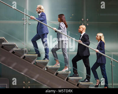 Multinationalen und multiethnischen corporate business Personen männlichen und weiblichen zu Fuß die Treppen hoch in einer Zeile in moderne Bürogebäude. Stockfoto