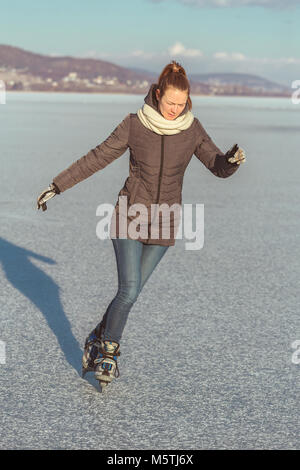 Hübsches blondes Mädchen skaten am Plattensee in Ungarn im Winter Stockfoto