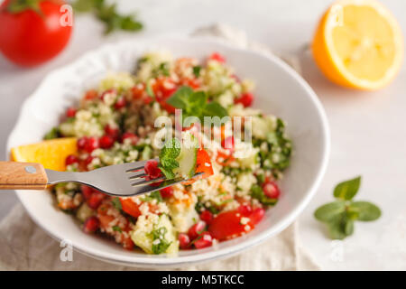 Tabbouleh Salat mit Tomaten, Gurken, Couscous, Minze und Granatapfel. Traditionelle orientalische oder arabische Gericht. Stockfoto