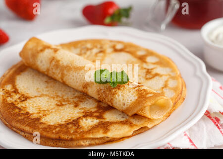 Dünne heißen Pfannkuchen mit Hüttenkäse und Erdbeeren. Gesunde, traditionelle Frühstück Konzept. Stockfoto