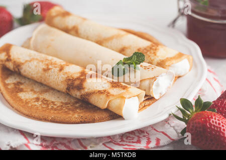 Dünne heißen Pfannkuchen mit Hüttenkäse und Erdbeeren. Gesunde, traditionelle Frühstück Konzept. Stockfoto