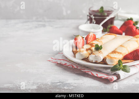 Dünne heißen Pfannkuchen mit Hüttenkäse und Erdbeeren. Gesunde, traditionelle Frühstück Konzept. Stockfoto