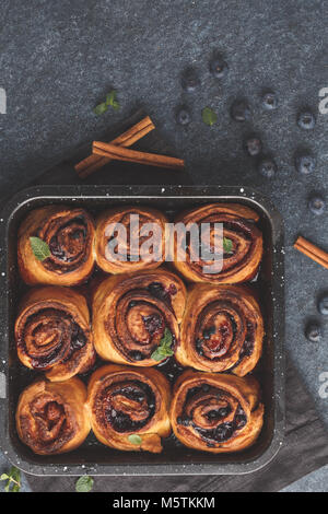 Hausgemachte Zimtkuchen mit Blaubeeren und Zimt in der auflaufform auf einem dunklen Hintergrund, Ansicht von oben Stockfoto