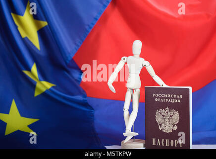 Russischen Pass und eine hölzerne Attrappe Figürchen auf russische und europäische Flagge. Übersetzung auf den Pass - Russische Föderation. Reisepass. Stockfoto