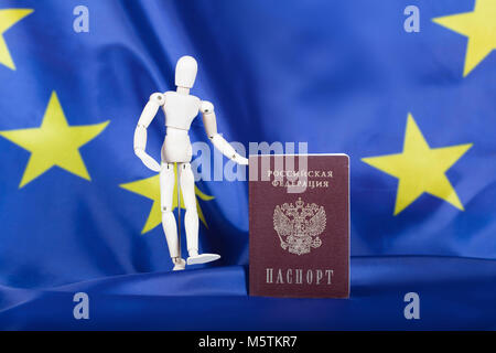 Russischen pass europäische Flagge. Hölzerne Attrappe Figur im Hintergrund. Übersetzung auf den Pass - Russische Föderation. Reisepass. Stockfoto