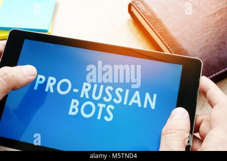 Mann hält Tablet mit Worten pro-russischen Bots. Russischen Internet propaganda Konzept. Stockfoto
