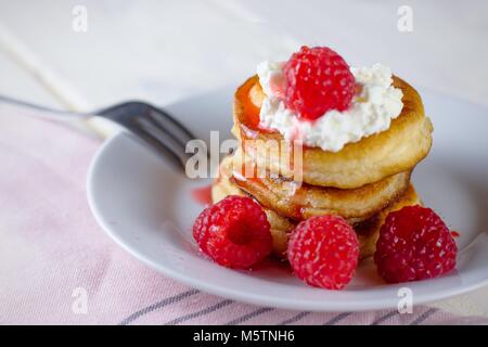 Ein Stapel von homemeade Pfannkuchen mit Sahne Pudding und Himbeeren gekrönt Stockfoto