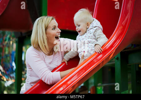 Kleines Mädchen und ihr schöne junge Mutter auf dem Spielplatz Stockfoto