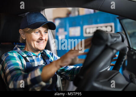 Senior Mechanikerin Instandsetzung ein Auto in eine Garage. Stockfoto