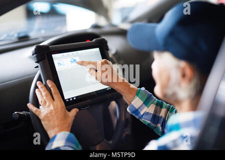 Senior Mechanikerin Instandsetzung ein Auto in eine Garage. Stockfoto