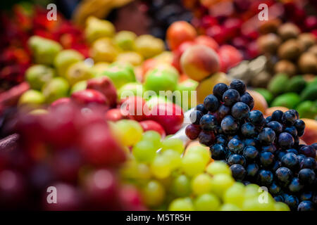 Stapel der Früchte (Trauben, rote und grüne Äpfel, Pfirsiche usw.) gesehen an den Obstmarkt von Paloquemao in Bogotá, Kolumbien angeordnet. Stockfoto