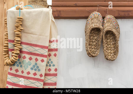 Gewebte Schuhe hängen an den Backofen, ein Bündel von Bagels und ein traditionelles Handtuch Stockfoto