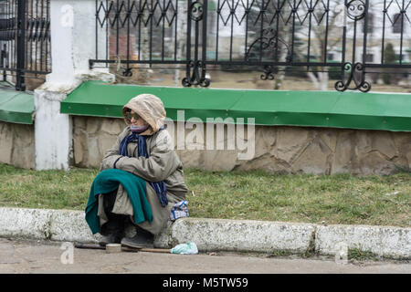 Eine alte Frau sitzt auf dem Bordstein auf die Straße und bittet um Geld. Der zentrale Platz der Stadt Tiraspol, Transnistrien. Stockfoto
