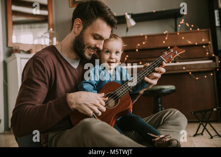 Vater lehre Tochter Gitarre im Zimmer zu Hause zu spielen Stockfoto