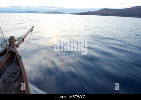 Segeln über den Saronischen Golf auf Aegina, Griechenland, auf einem kleinen Segelboot namens Chryssopigi in der Abenddämmerung. Stockfoto