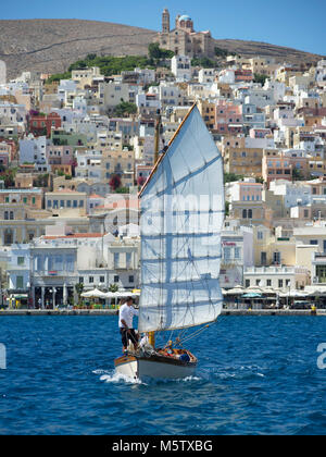 Das Segelboot Chryssopigi Segel aus Syros Hafen, in Griechenland. Die griechisch-orthodoxe Kirche der Auferstehung Christi sichtbar ist. Stockfoto