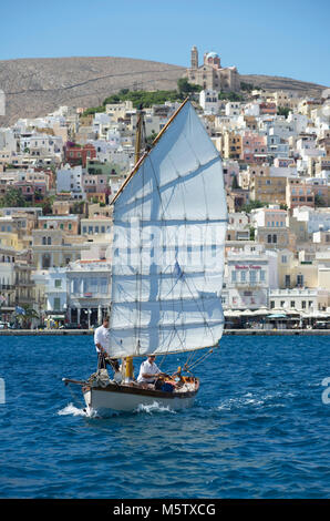 Das Segelboot Chryssopigi Segel aus Syros Hafen, in Griechenland. Die griechisch-orthodoxe Kirche der Auferstehung Christi sichtbar ist. Stockfoto