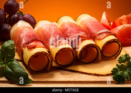 Käse und Schinken auf Schneidebrett auf hölzernen Tisch Stockfoto